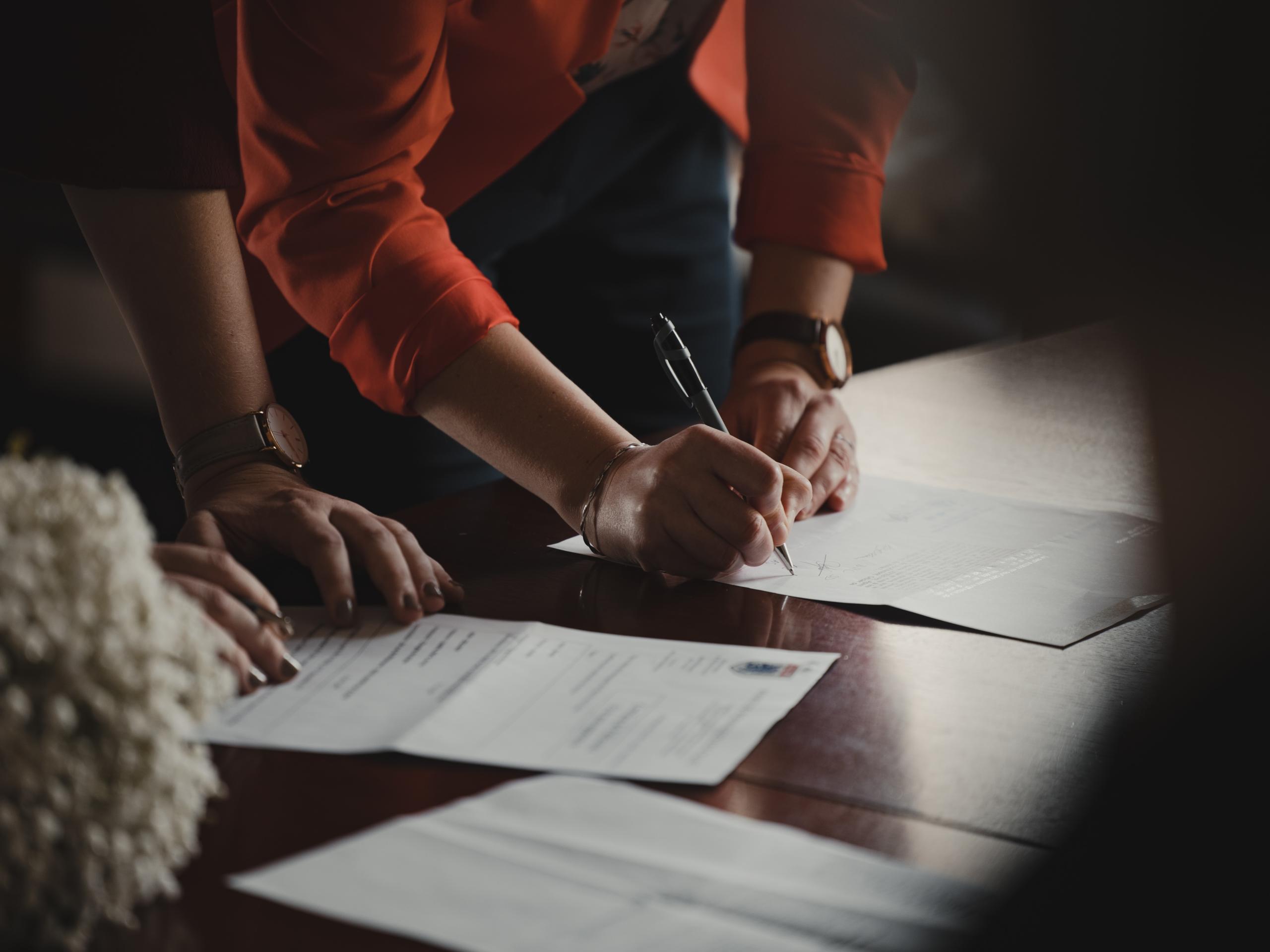 Two people at a table, one is writing on a piece of paper.